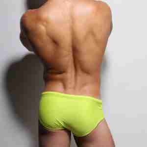 Muscled man flaunting ZLC Aqua Lime Swimwear, showcasing his bubble butt