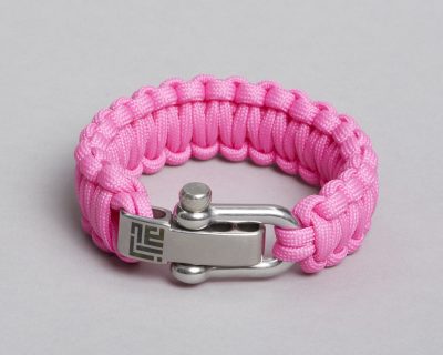 Handmade pink paracord bracelet with ZLCOPENHAGEN logo on metal clasp, using macramé technique for breast cancer awareness.
