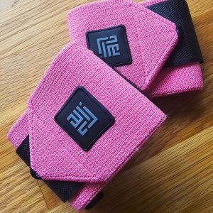 Baby pink wrist wraps providing solid support, made of durable fabric with a secure Velcro closure