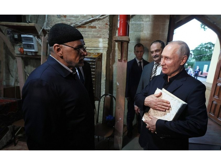 Vladimir Putin visiting a mosque in Russia and meeting Muslim leaders while holding a religious book